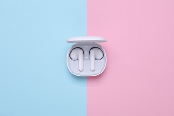 Wireless earphones with charging case on blue pink background