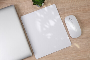 Mockup of white blank computer mouse pad or mat with props, mouse and laptop on table. Top view....
