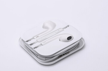 White wired earphones with case on a white background