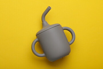 Silicone drinking bowl with a straw for baby on a yellow background