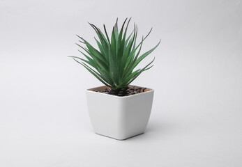 Decorative artificial plant in a pot on a gray background