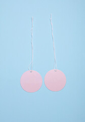 Round pink price tags on ropes, blue pastel background