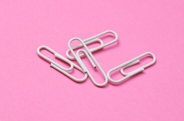 White paper clips on pink background