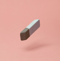 Eraser levitating on pink background with shadow.