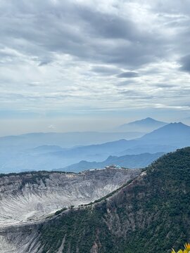 Breathtaking mountain landscape with layered hills, a volcanic crater, and dramatic clouds, offering a serene and picturesque view