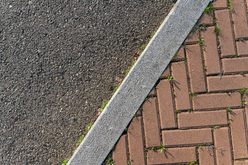 Self-locking bricks and asphalt road junction. Functional and weather-resistant material. Self-locking designed floors without mortar that facilitate maintenance and drainage.