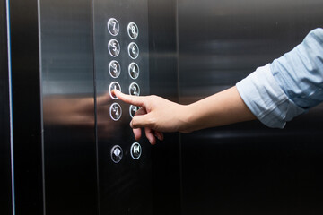 A finger presses the elevator button.