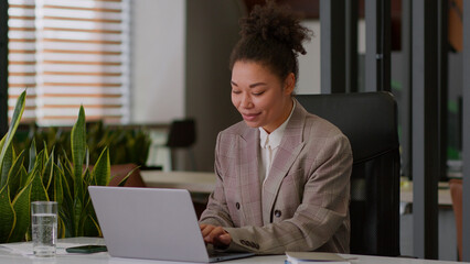 Fototapeta premium Female pc user African American ethnic woman lady business employer smiling positive businesswoman worker manager agent online working laptop computer happy girl sing listen music in office good mood