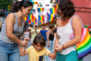 Obraz premium Lesbian mothers holding hands with their son at gay pride parade
