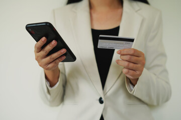 Female hands holding credit card, shopping trolley and smartphone for secure payment, shopping and paying online, ordering products and booking flight tickets, using banking service by entering data.