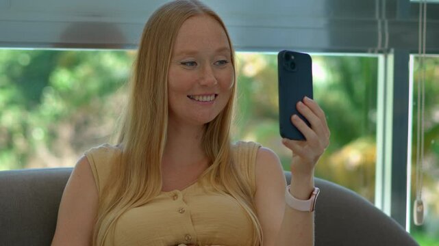 Happy young pregnant woman on a video call with family, proudly showing a 3D ultrasound photo of her baby from a recent doctor's visit. Joyful pregnancy announcement and family connection concept