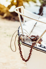 Boat anchor detail on sandy beach with blurred sunny background