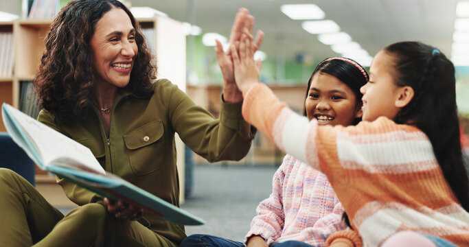 School kids, teacher and high five with book at library for achievement, learning and celebration for progress. Children, reading and story with woman for goals, excited or cheers language at academy