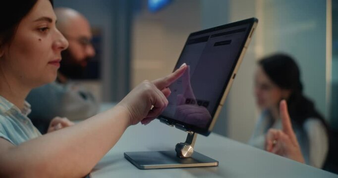 Passengers at Airport Check-in Counter: Side View of Woman Putting Finger on Touch Screen for Biometric Fingerprint Scanning. Personal ID Data Verification for Flight. International Airport Terminal.