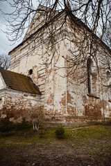 Ruined historic building with cracks and peeling paint in a deserted location under a cloudy sky....