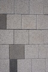 An image of rectangular tiles arranged in a grid pattern. The tiles have a light gray speckled texture, with some darker gray tiles randomly interspersed, creating contrast and visual interest.