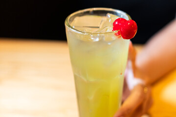 Refreshing Yellow Cocktail with Cherry Garnish