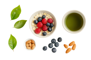 A flat lay of a healthy breakfast spread on a white background, including oatmeal with fresh berries, a cup of green tea, and a few almonds