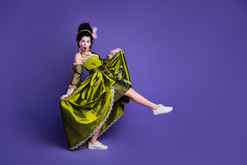 Elegant woman in green retro dress posing against violet backdrop blending vintage and modern...
