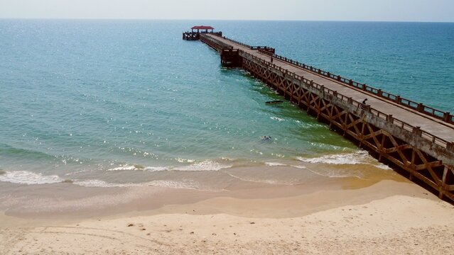 Pier Overlooking the Ocean: A long wooden pier extends gracefully over the calm turquoise waters of the ocean, leading the eye toward the horizon on a clear day. 