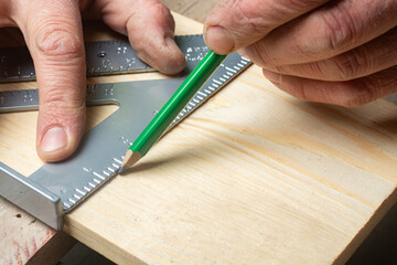 A carpenter measures a right angle on a wooden board.