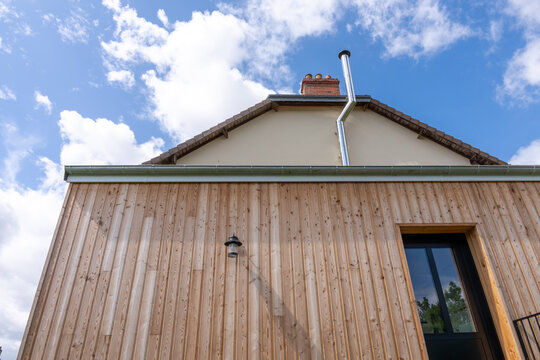 Extension moderne d&rsquo;une maison avec bardage en bois, contrastant harmonieusement avec la structure ancienne en pierre.