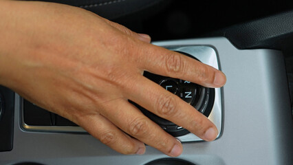 Driver's hand shifts the car gearbox modes such as parking and drive mode and parking brakes. Automatic electronic transmission and gear shift, P Park to D Drive and back in modern cars.