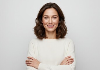 Fototapeta premium Woman in white sweater with arms crossed on gray background for confident portrait concept
