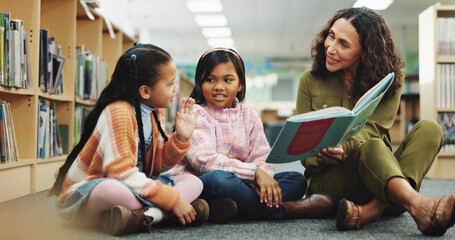 Girl, teacher and teaching with reading book at library for development, learning or study with guide. School kids, storytelling and woman with help, education and language for knowledge at academy © peopleimages.com