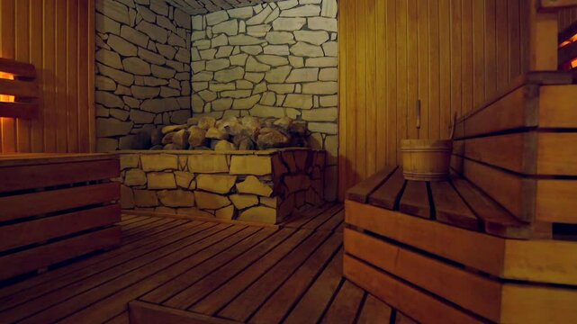 Beautiful Sauna with Lots of Large Stones and Wooden Shelves and Soft Light. Sauna is a Room or Building Designed as a Place to Experience Dry or Wet Heat Sessions.