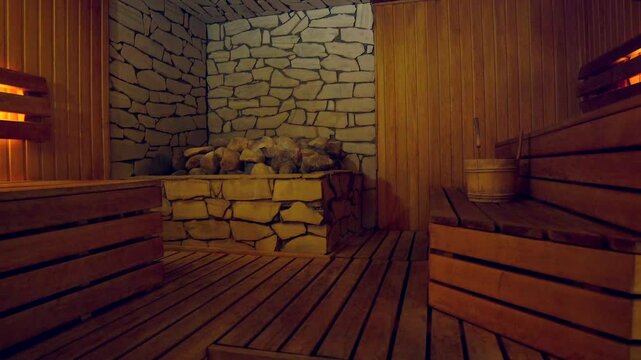 Beautiful Sauna with Lots of Large Stones and Wooden Shelves and Soft Light. Sauna is a Room or Building Designed as a Place to Experience Dry or Wet Heat Sessions.