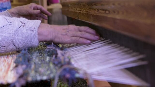 An Old Woman With Large Looms Weaves a Colorful, Decorative Tapestry or Carpet. Weaving is a Method of Textile Production in Which Two Sets of Yarns are Interlaced to Form a Fabric or Cloth.