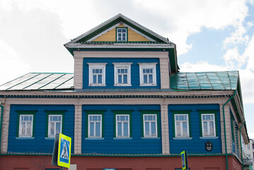 a blue wooden antique two-storey house with a yellow attic and a green iron roof