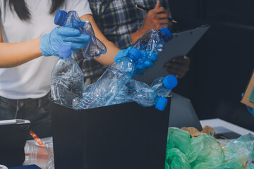 Close-up of female hands from a family collecting plastic waste and bottles from the ground. They...