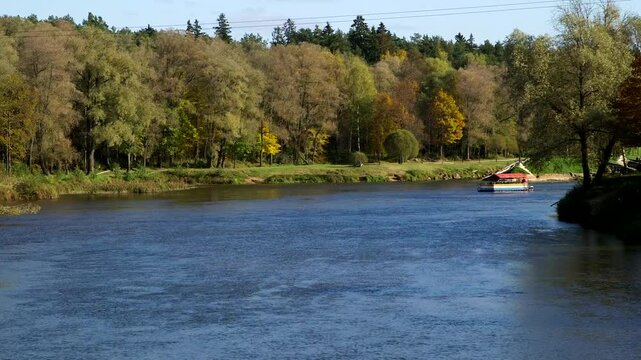 A Small Colorful Tourist Boat - Raft, is Sailing Along the River in Autumn. Valmiera is One of the Oldest Cities in Latvia, Having Been a Member of the Hanseatic League.