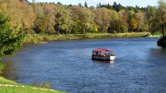 A Small Colorful Tourist Boat - Raft, is Sailing Along the River in Autumn. Valmiera is One of the Oldest Cities in Latvia, Having Been a Member of the Hanseatic League.