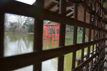 Obraz premium A peaceful park by a calm lake, lined with striking wooden monuments. Surrounded by greenery, the scene reects tranquility and natural beauty in perfect harmony