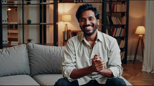 A man sits on a sofa in a cozy living room.