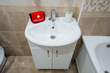In the bathroom, there is a sink that has a first aid kit placed on top of it, ready for any emergencies that might arise and to ensure safety and wellbeing when needed