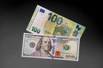 One hundred euro and one hundred dollar banknotes on a black background. The choice. Studio shooting.
