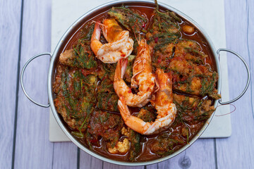 Spicy soup with mushrooms, lemon, coconut milk and chili in white bowl on wooden table background.