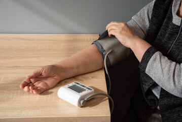 woman independently measures her blood pressure at home, her hand close-up.