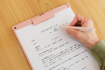 カウンセリングシートに書き込む女性の手元
