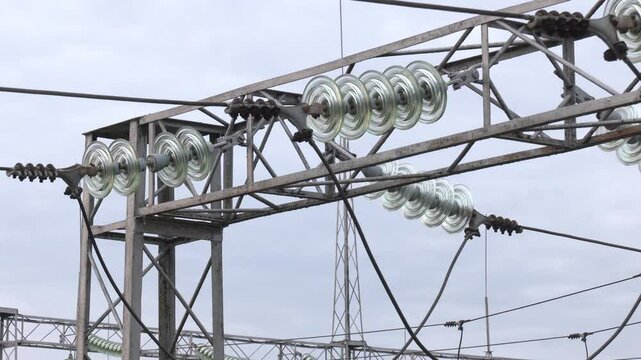 A concrete tower of high voltage (110 kV) overhead electricity line and glass insulators. A garland of insulators on electric wires of a metal high-voltage support.