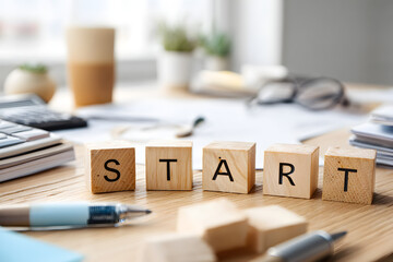 Wooden blocks spelling start, modern workspace filled with stationery and plants, motivational theme for new projects.