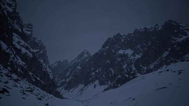 Snow-covered mountain range under moody sky, dramatic cold landscape