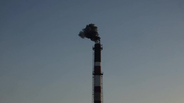 Industrial chimney emitting smoke into sky, symbol of pollution and environmental impact