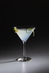 Fresh daiquiri cocktail with lemon peel on on dark shadowy background