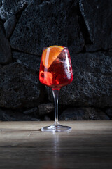 Fresh Spritz cocktail with orange slice and ice, on lava stones background
