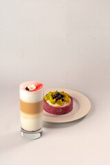 Dessert on white plate and sweet cocktail in glass on white table